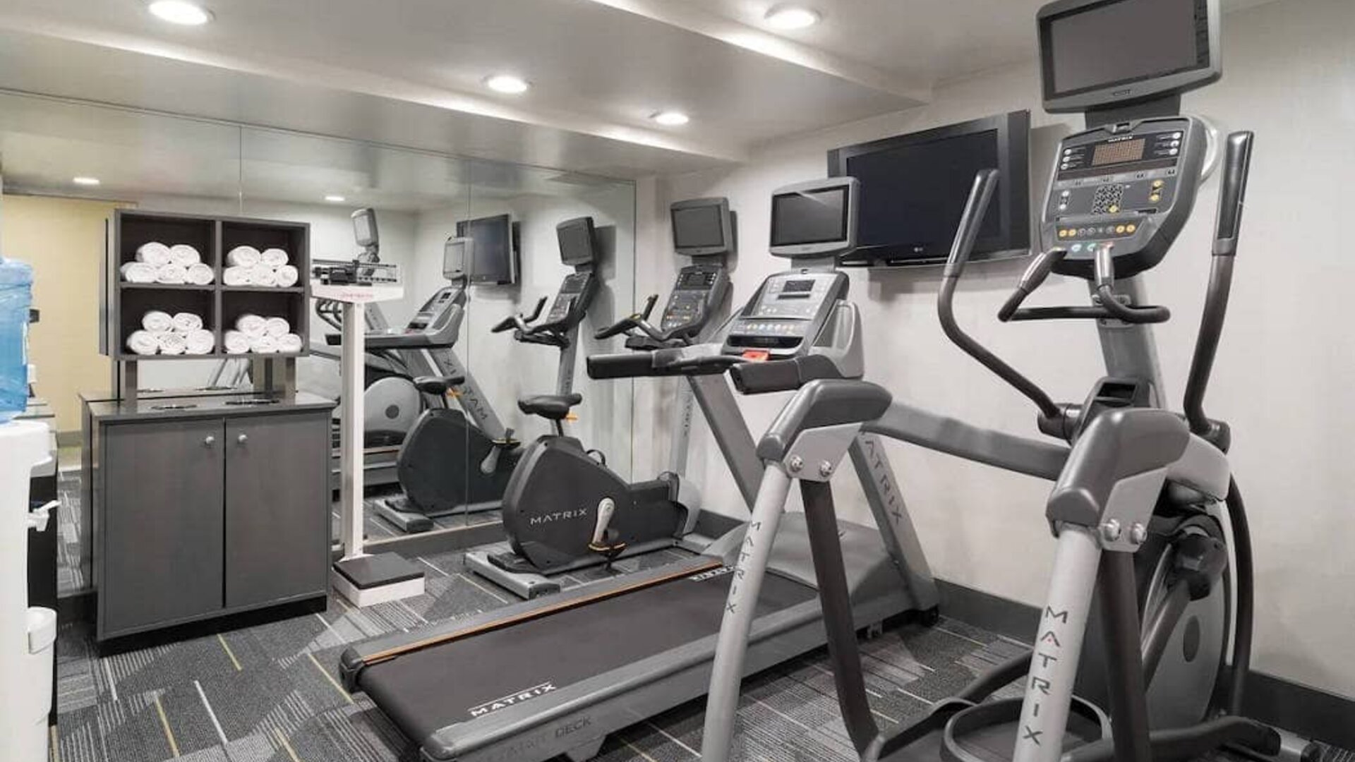 Various exercise machines, towels, and TV in the hotel’s fitness center.