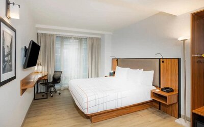 Guest room in La Quinta Times Square South, complete with double bed, large window, TV, and workspace.