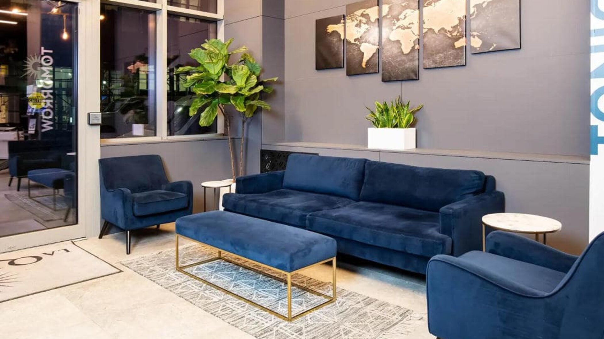 The lounge located in La Quinta Times Square South’s lobby, with comfy seating and potted plants.