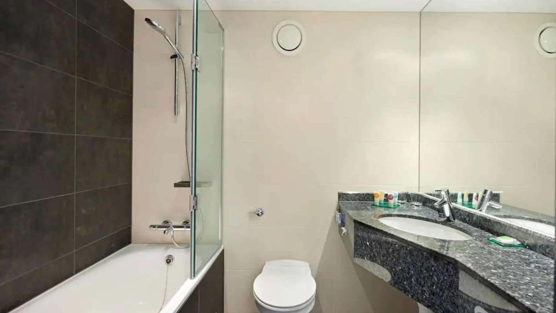 Private guest bathroom with shower and bath at Hyatt Place London Heathrow Airport.