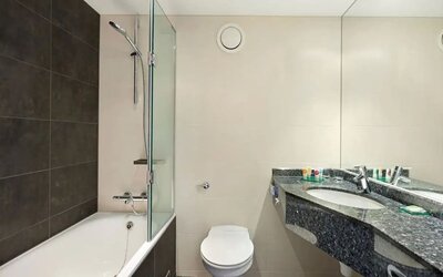 Private guest bathroom with shower and bath at Hyatt Place London Heathrow Airport.