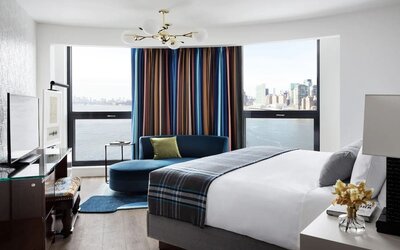 Spacious king bed with TV and seating area at Graduate New York.