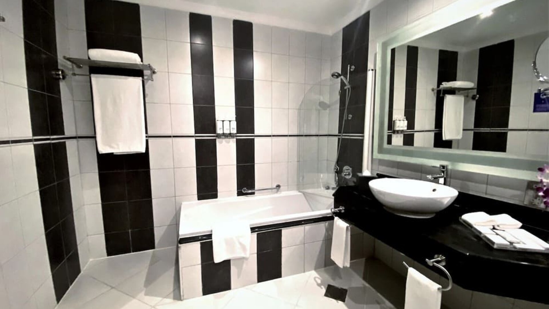 Guest bathroom with shower and bath at Millennium Central Doha.