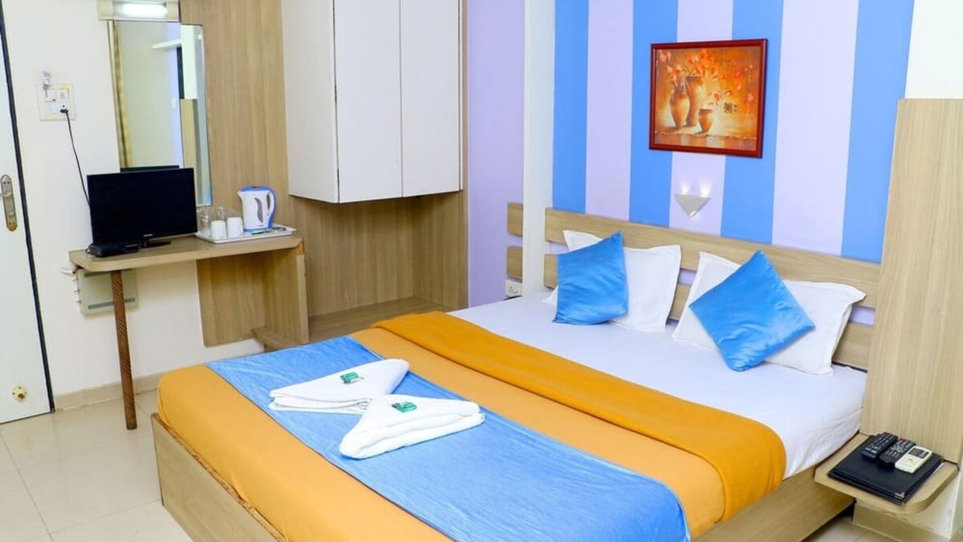 King bed in brightly lit room at Hotel Alka Residency.