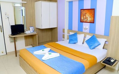 King bed in brightly lit room at Hotel Alka Residency.