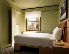 Cozy guest room with natural light, city views, and minimalist modern furnishings at Row NYC.
