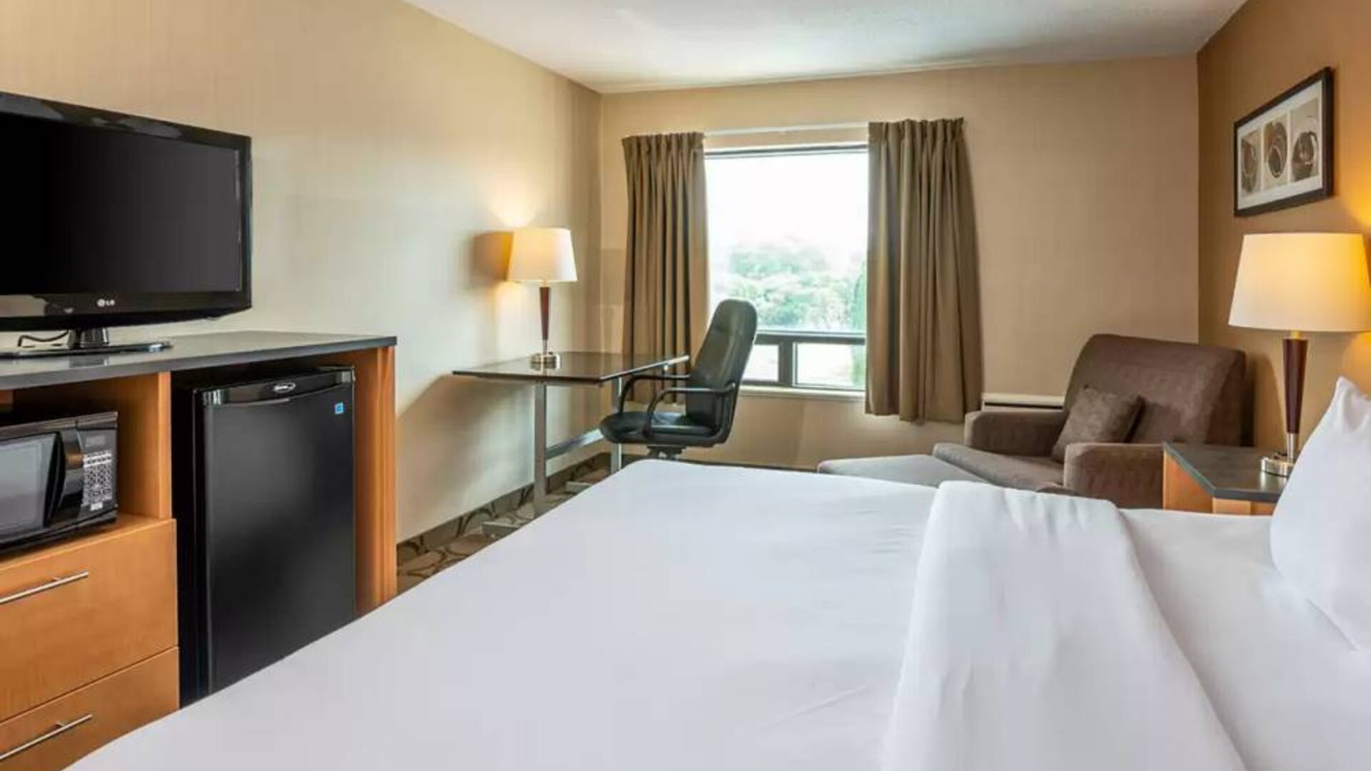 Double bed guest room in Comfort Inn Truro, with sofa and TV.