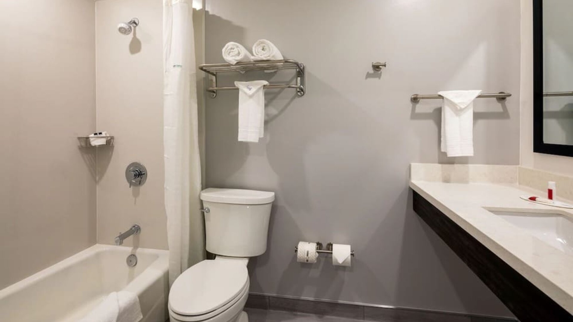 Private guest bathroom with combined shower and tub at Travelodge LAX By Wyndham.