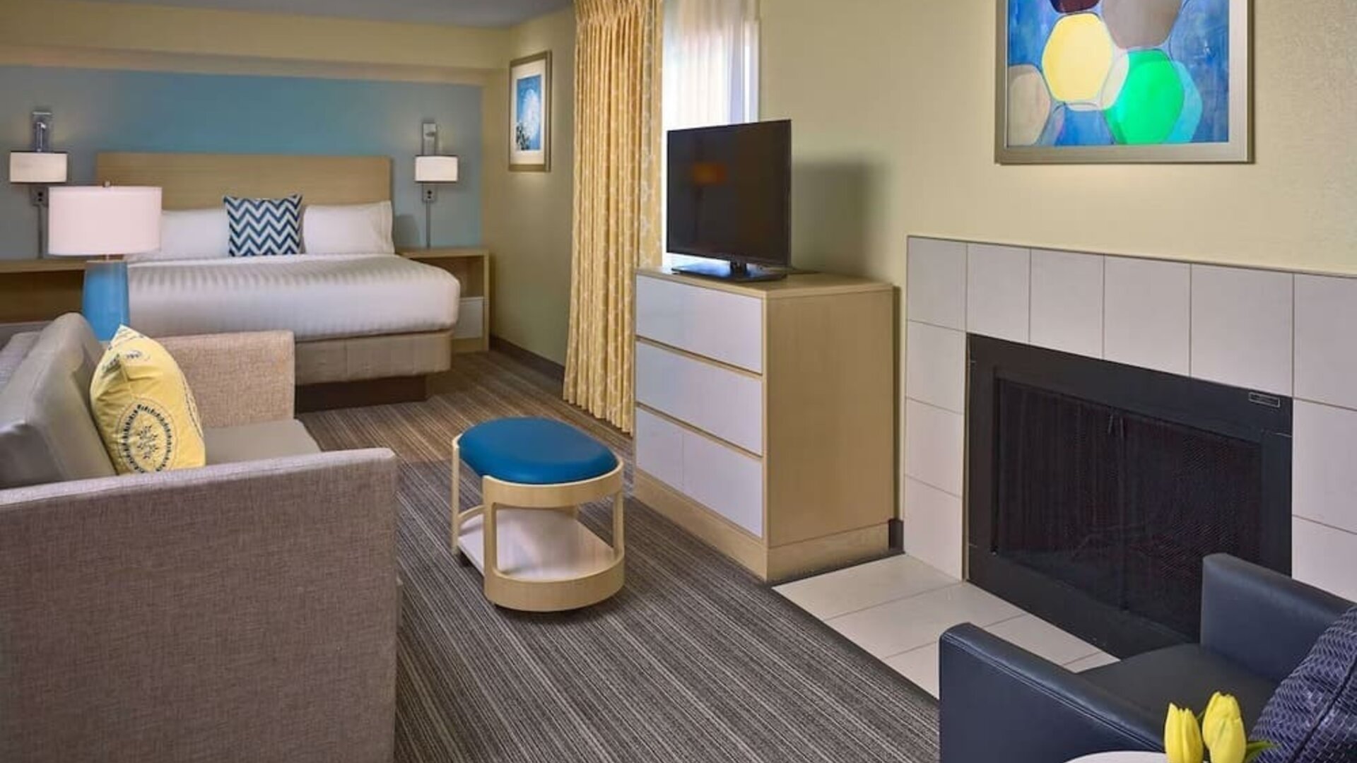 Double bed guest room in Sonesta ES Suites Tucson, including lounge with sofa, armchair, and TV.
