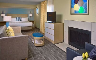 Double bed guest room in Sonesta ES Suites Tucson, including lounge with sofa, armchair, and TV.