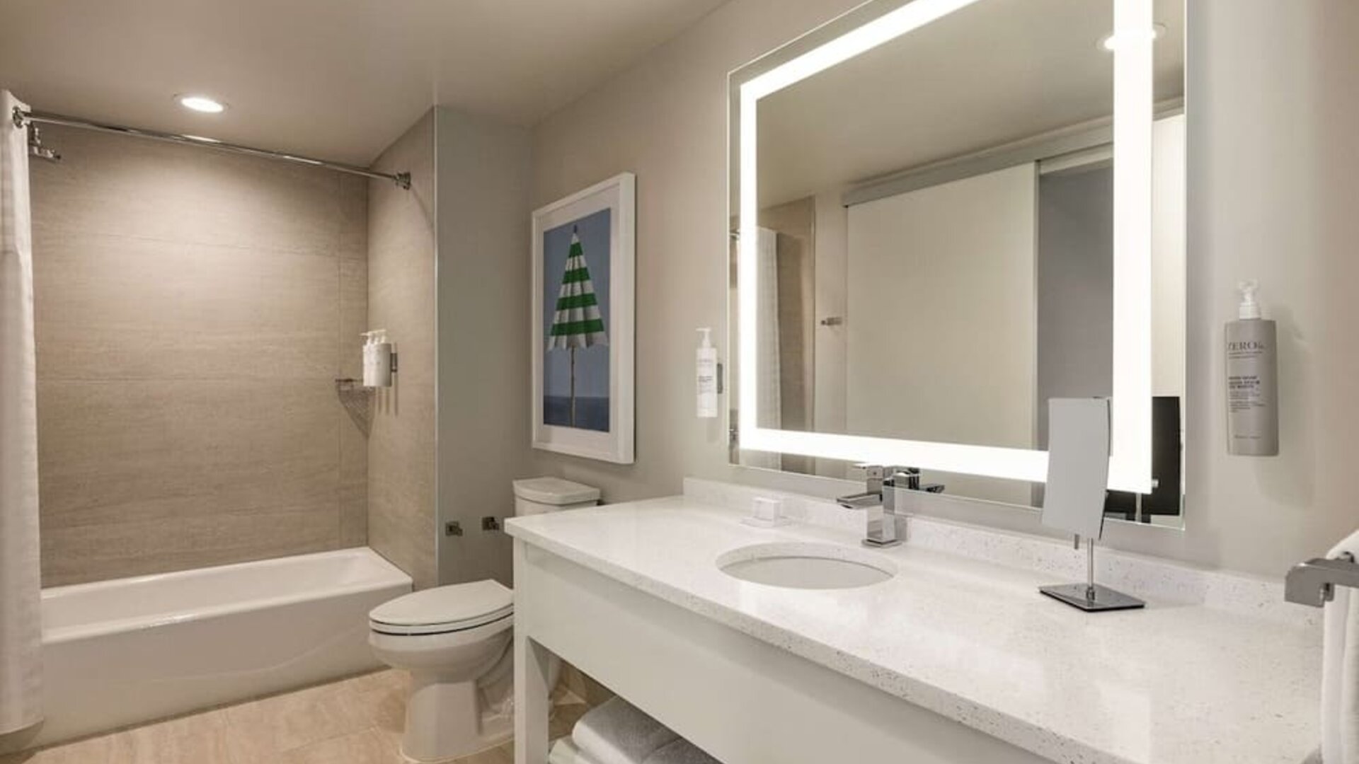 Private guest bathroom with tub and free toiletries at Embassy Suites By Hilton Panama City Beach Resort.
