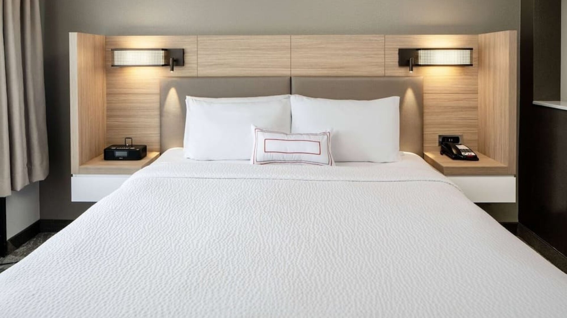 Sonesta Select Nashville Airport Suites deluxe king bed room, featuring bedside lamps and telephone.