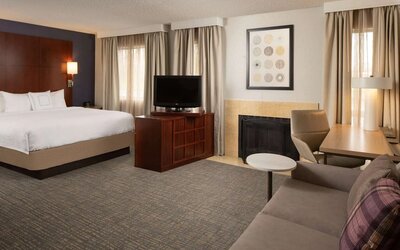 Sonesta ES Suites Nashville Brentwood king bed guest room, furnished with sofa, desk, and TV.