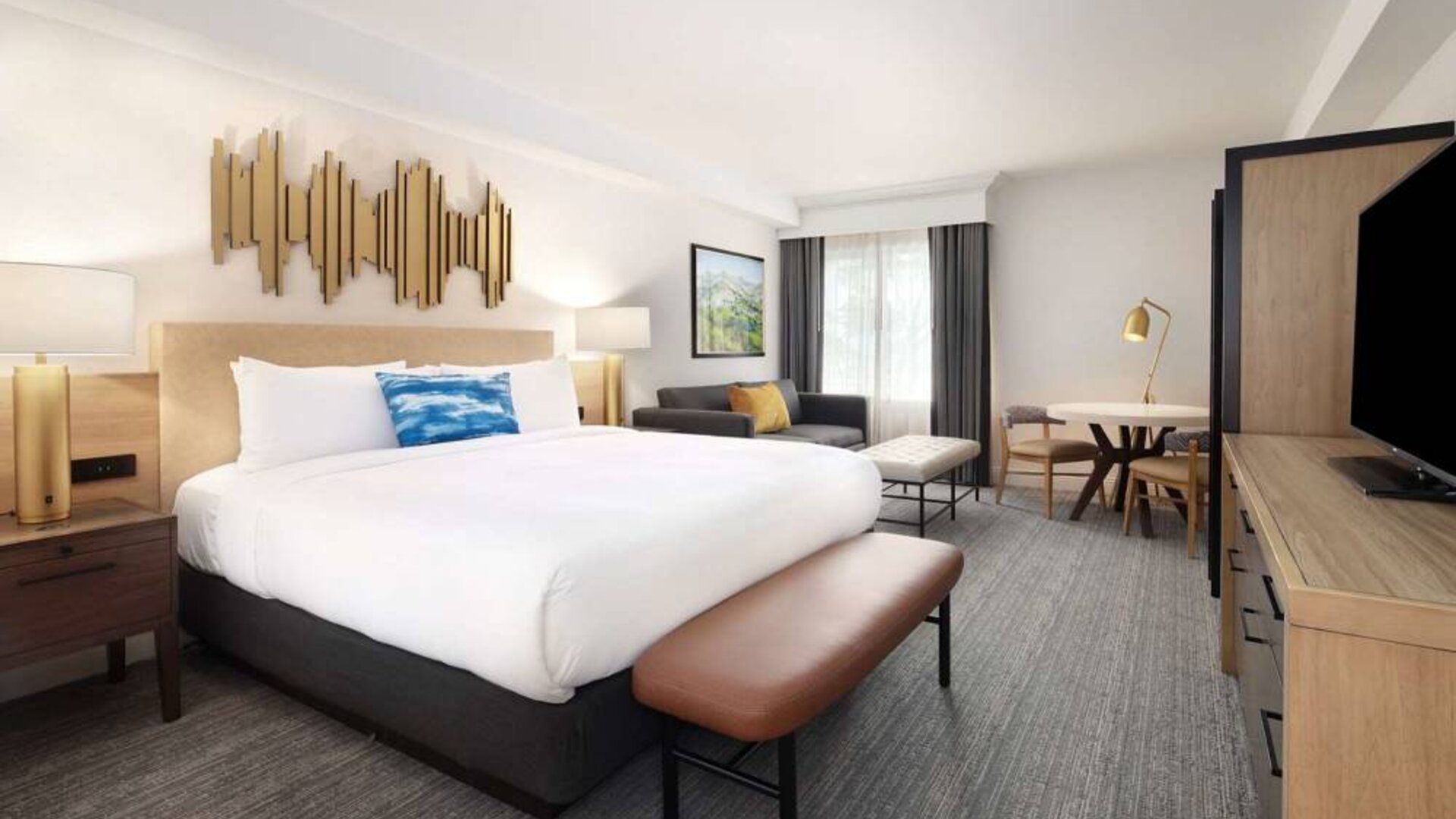 Sonesta Silicon Valley double bed guest room, featuring sofa, table and chairs, window, and TV.