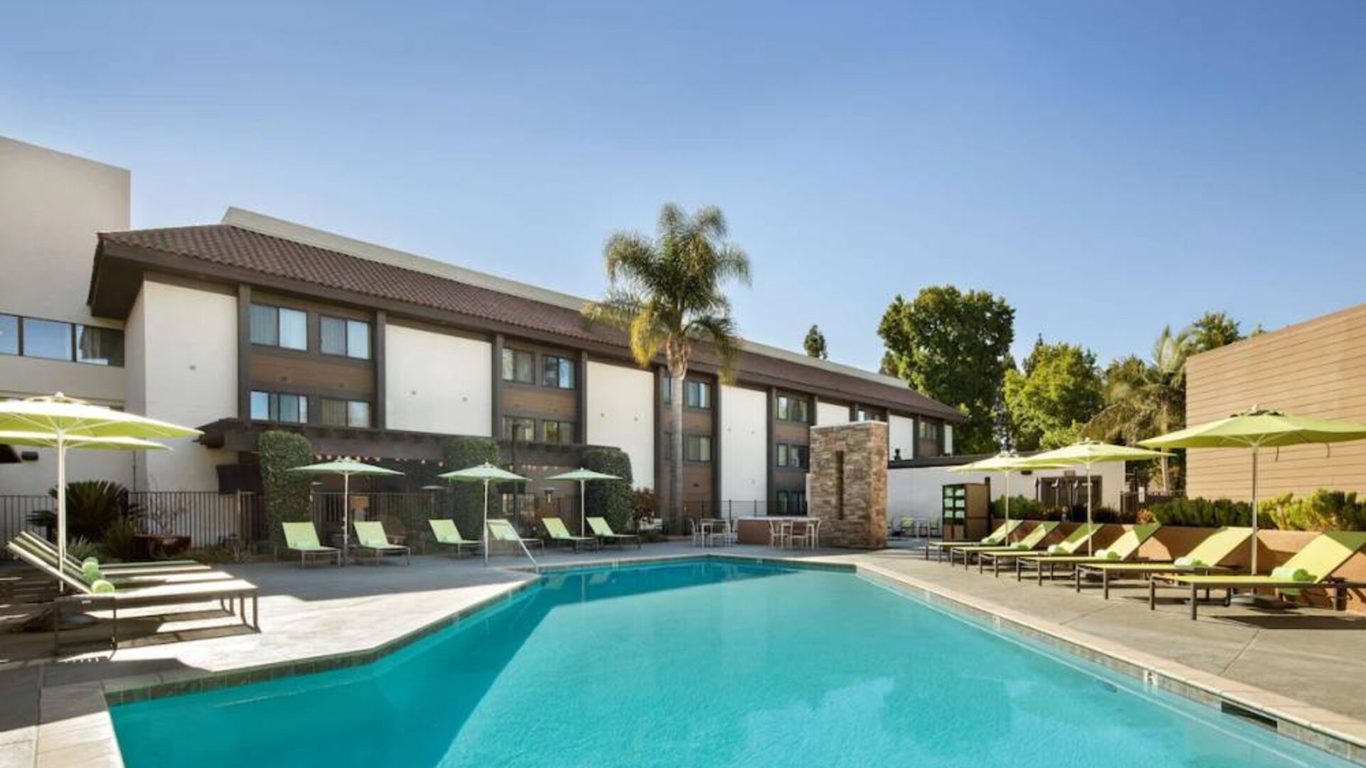 The outdoor pool of Sonesta Silicon Valley has nearby sun loungers, tables and chairs, and plenty of shade available.