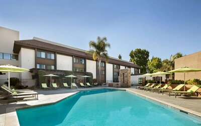 The outdoor pool of Sonesta Silicon Valley has nearby sun loungers, tables and chairs, and plenty of shade available.