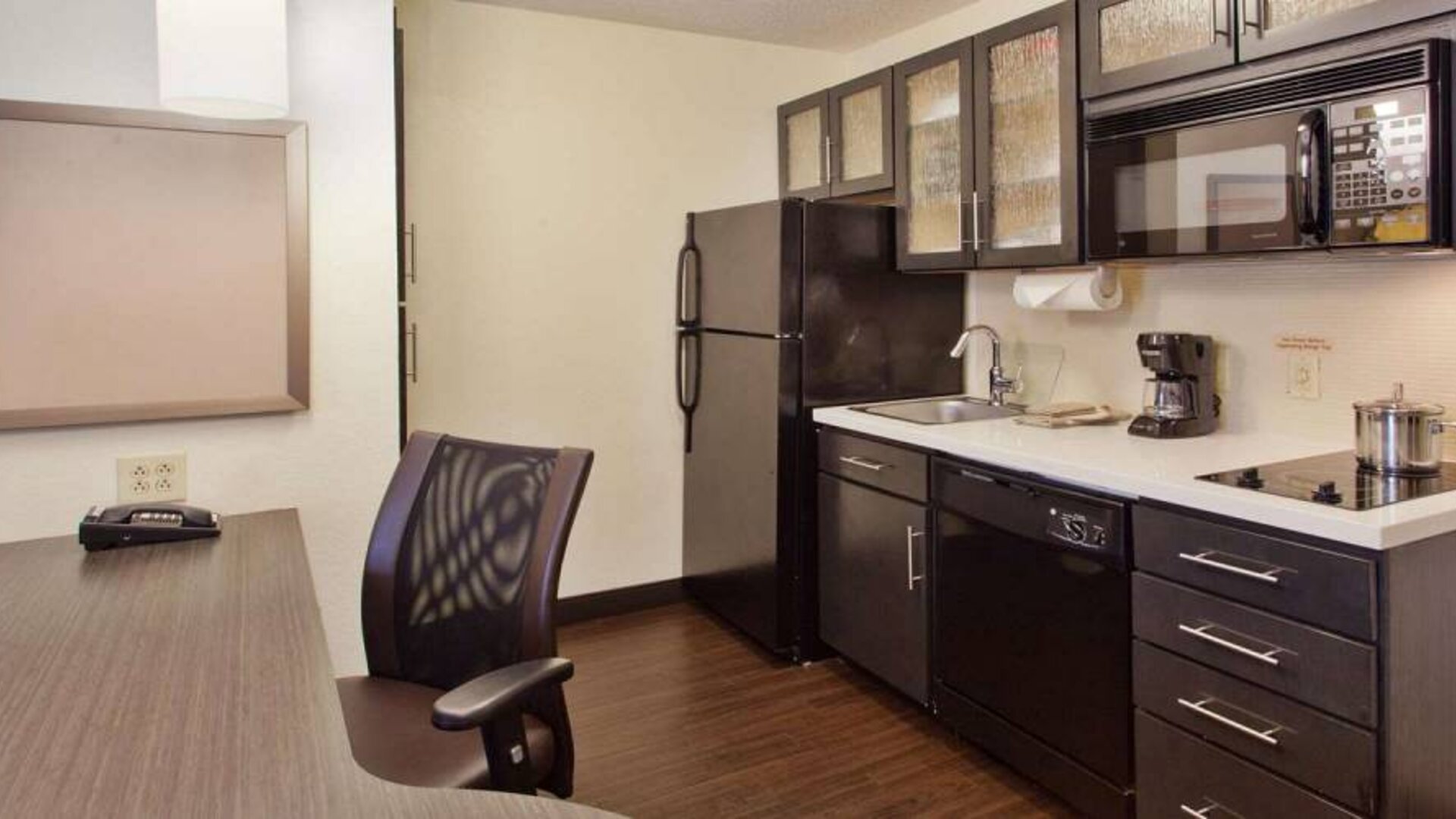 Sonesta Simply Suites Cleveland North Olmsted Airport guest room workspace desk and chair, and adjacent kitchenette.