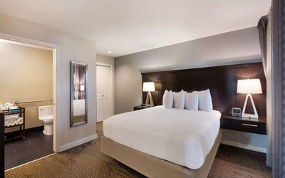 Double bed guest room in Sonesta ES Suites Dulles Airport, with tall mirror and ensuite bathroom.