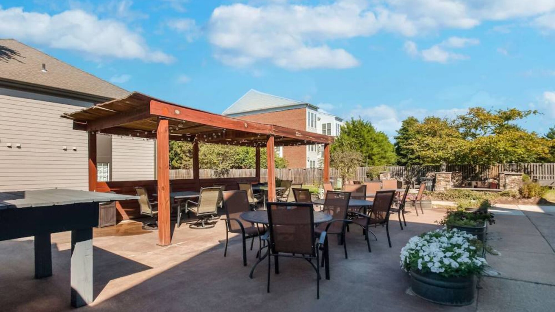 Sonesta ES Suites Dulles Airport’s terrace features tables and chairs, some under cover, and potted plants.