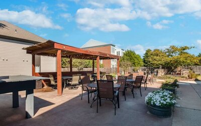 Sonesta ES Suites Dulles Airport’s terrace features tables and chairs, some under cover, and potted plants.