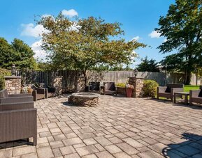 The hotel’s patio has armchairs, coffee tables, and nearby greenery.