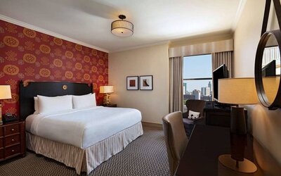 The Stephen F Austin Royal Sonesta Hotel double bed guest room, including window and workspace desk and chair.