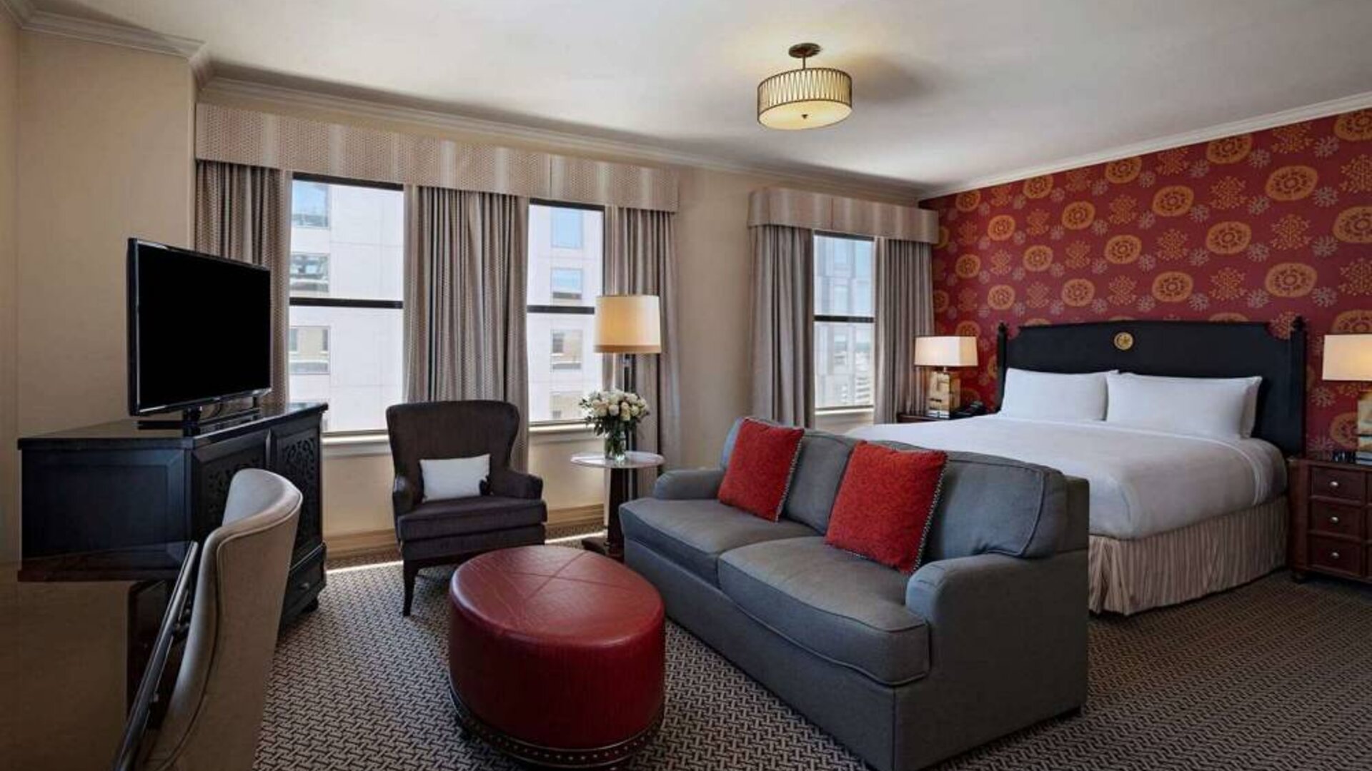 Double bed guest room in The Stephen F Austin Royal Sonesta Hotel, furnished with sofa, chair, desk, and television.