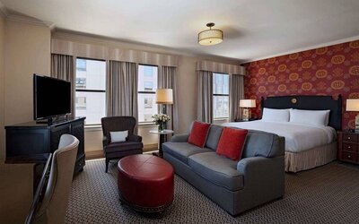 Double bed guest room in The Stephen F Austin Royal Sonesta Hotel, furnished with sofa, chair, desk, and television.