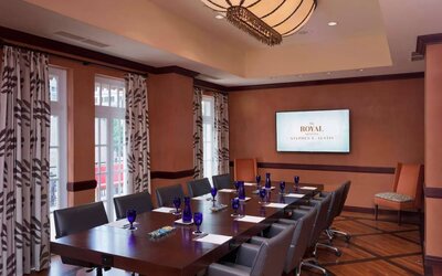 The Stephen F Austin Royal Sonesta Hotel meeting room, with long wooden table, ten swivel chairs, and wall-mounted television.