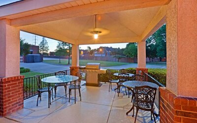 The hotel’s gazebo provides outdoor tables and chairs under cover, with greenery nearby and a barbecue.