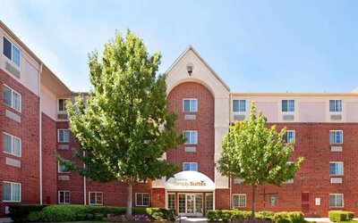 Sonesta Simply Suites Arlington’s exterior has clear signage, beautiful lawns, and towering trees.