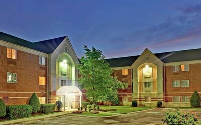 Sonesta Simply Suites Nashville Brentwood’s exterior is brightly lit and has well-tended lawns, bushes, and trees.