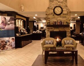 The hotel’s lobby has comfortable seating, a coffee table, reading material, and a cozy fireplace.