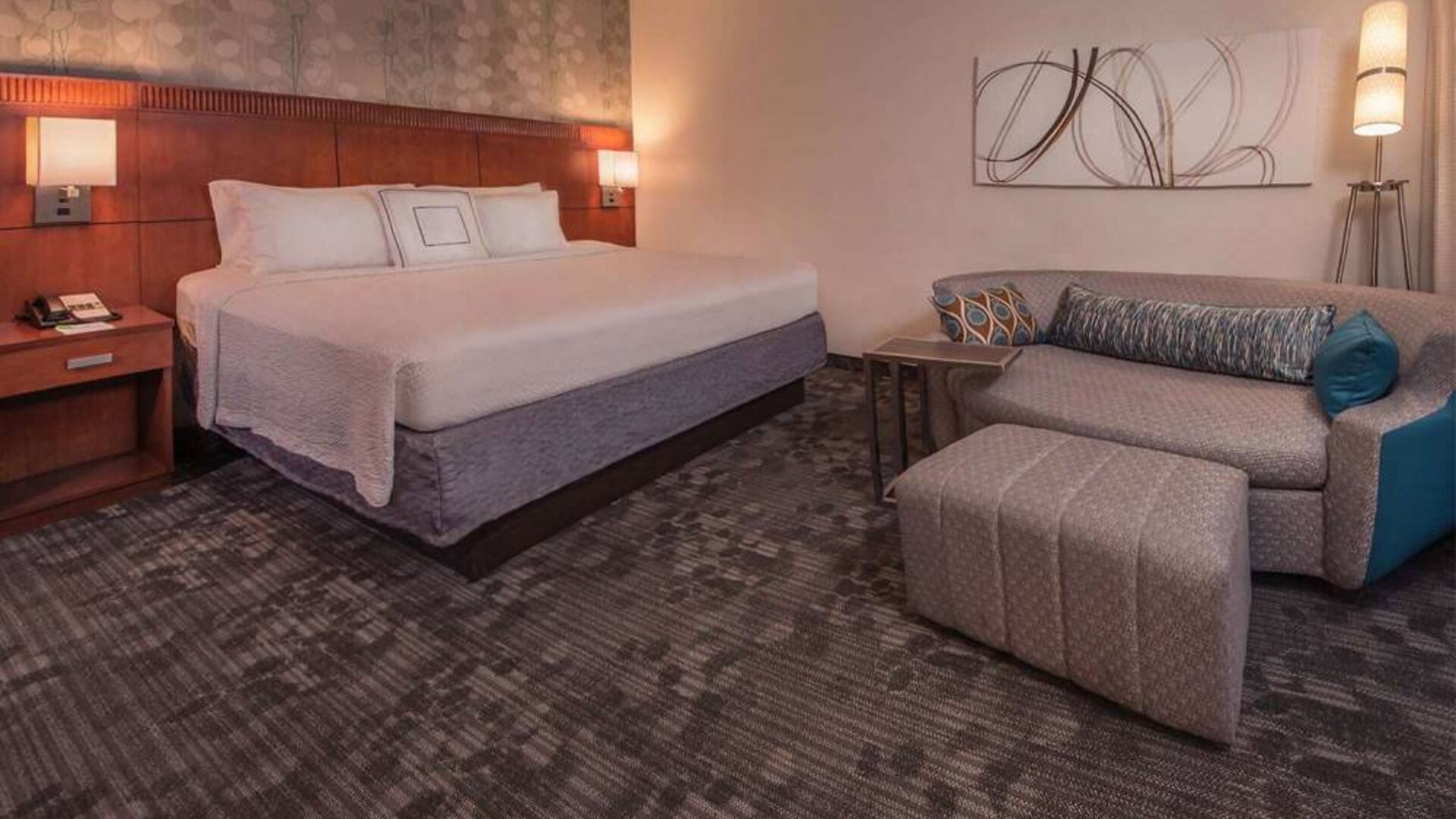 Double bed guest room in Sonesta Select Arlington Rosslyn, furnished with wall art, sofa, and coffee table.