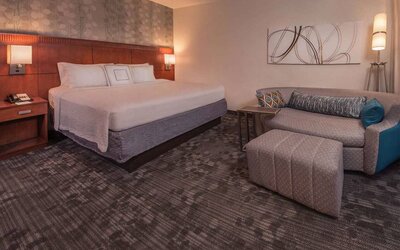 Double bed guest room in Sonesta Select Arlington Rosslyn, furnished with wall art, sofa, and coffee table.