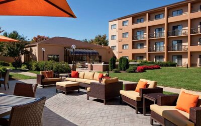 The hotel terrace is furnished with shaded tables and chairs, plus armchairs and sofa seating with adjacent coffee tables.
