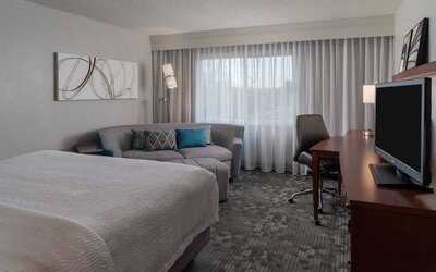 Double bed guest room in Sonesta Select Chattanooga Hamilton Place, featuring sofa, TV, desk, and window.