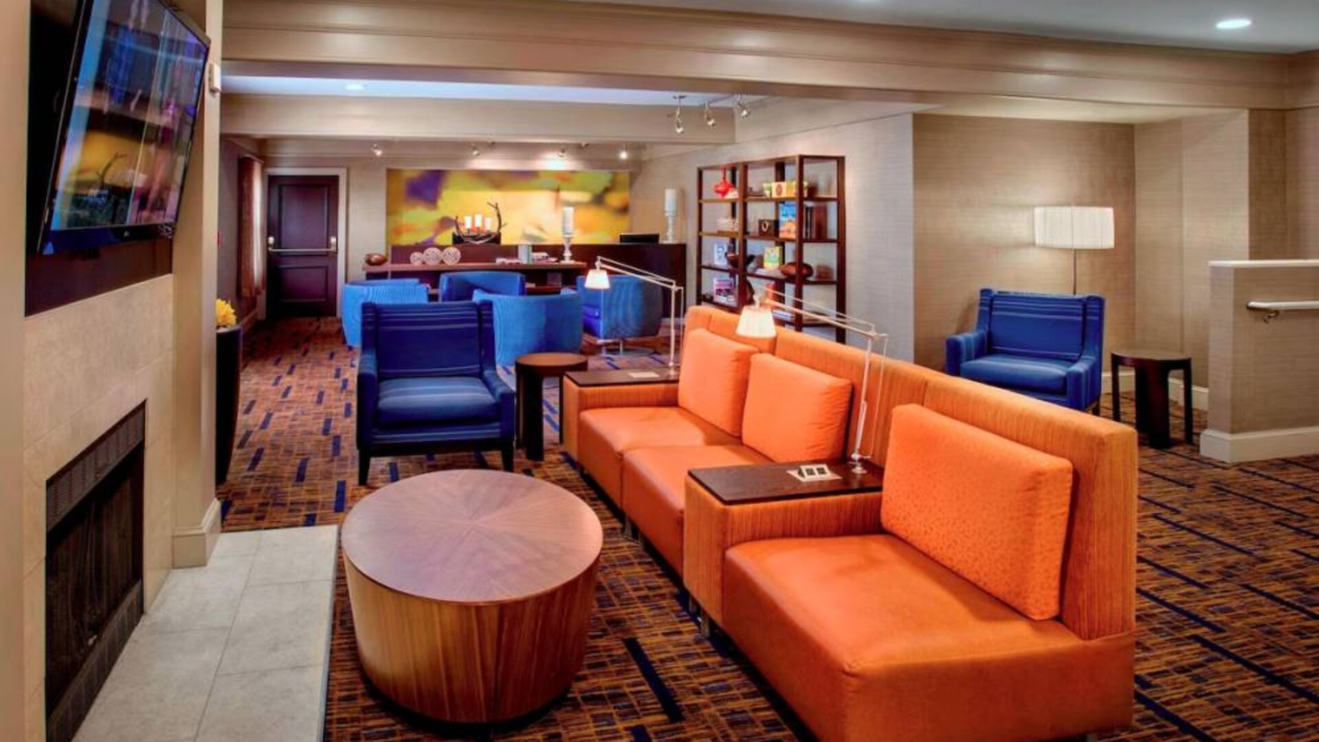 The hotel’s lobby lounge is furnished with armchair and sofa seating, coffee tables, a large television, and a fireplace.