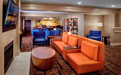 The hotel’s lobby lounge is furnished with armchair and sofa seating, coffee tables, a large television, and a fireplace.