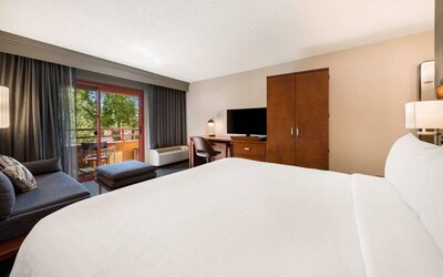 Double bed guest room in Sonesta Select San Jose Airport, with workspace desk and chair, plus TV.