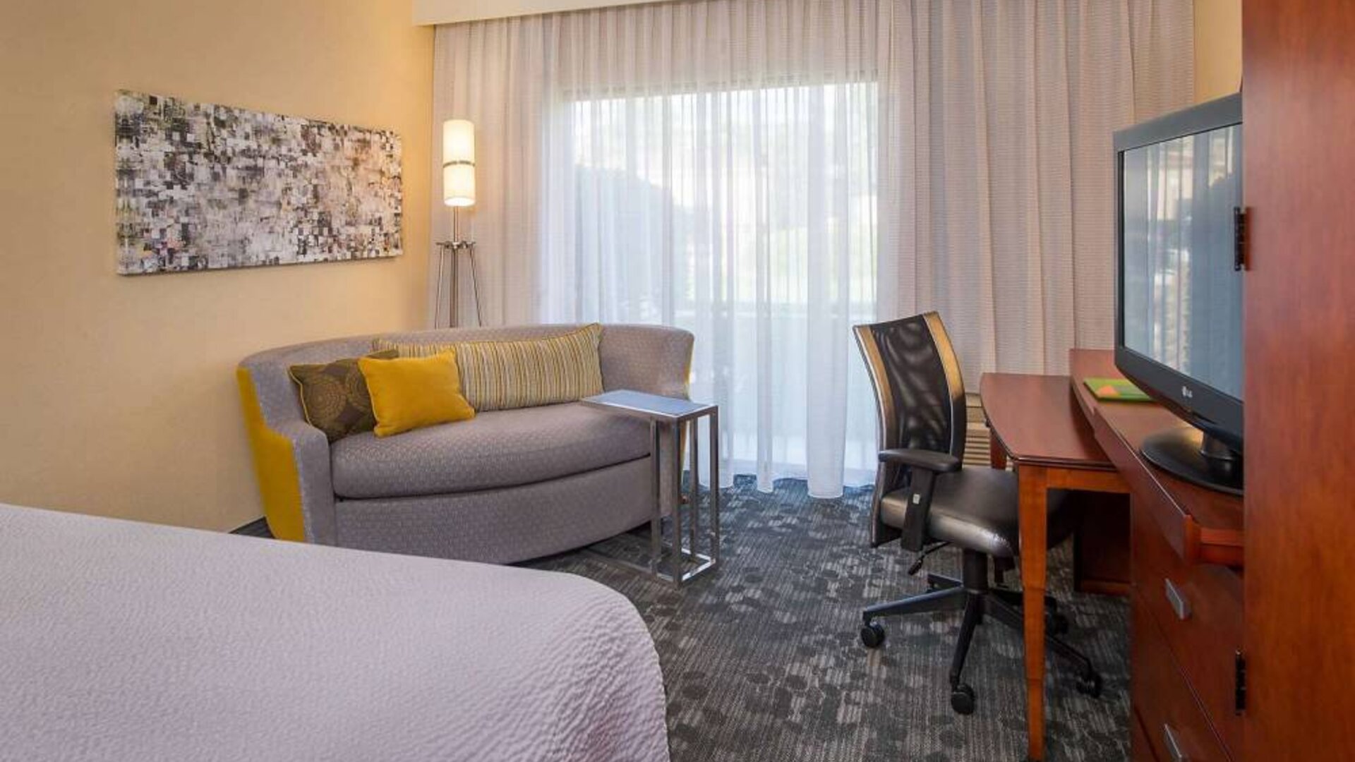 Double bed guest room in Sonesta Select Charlotte University Research Park, furnished with TV, chair, and sofa.