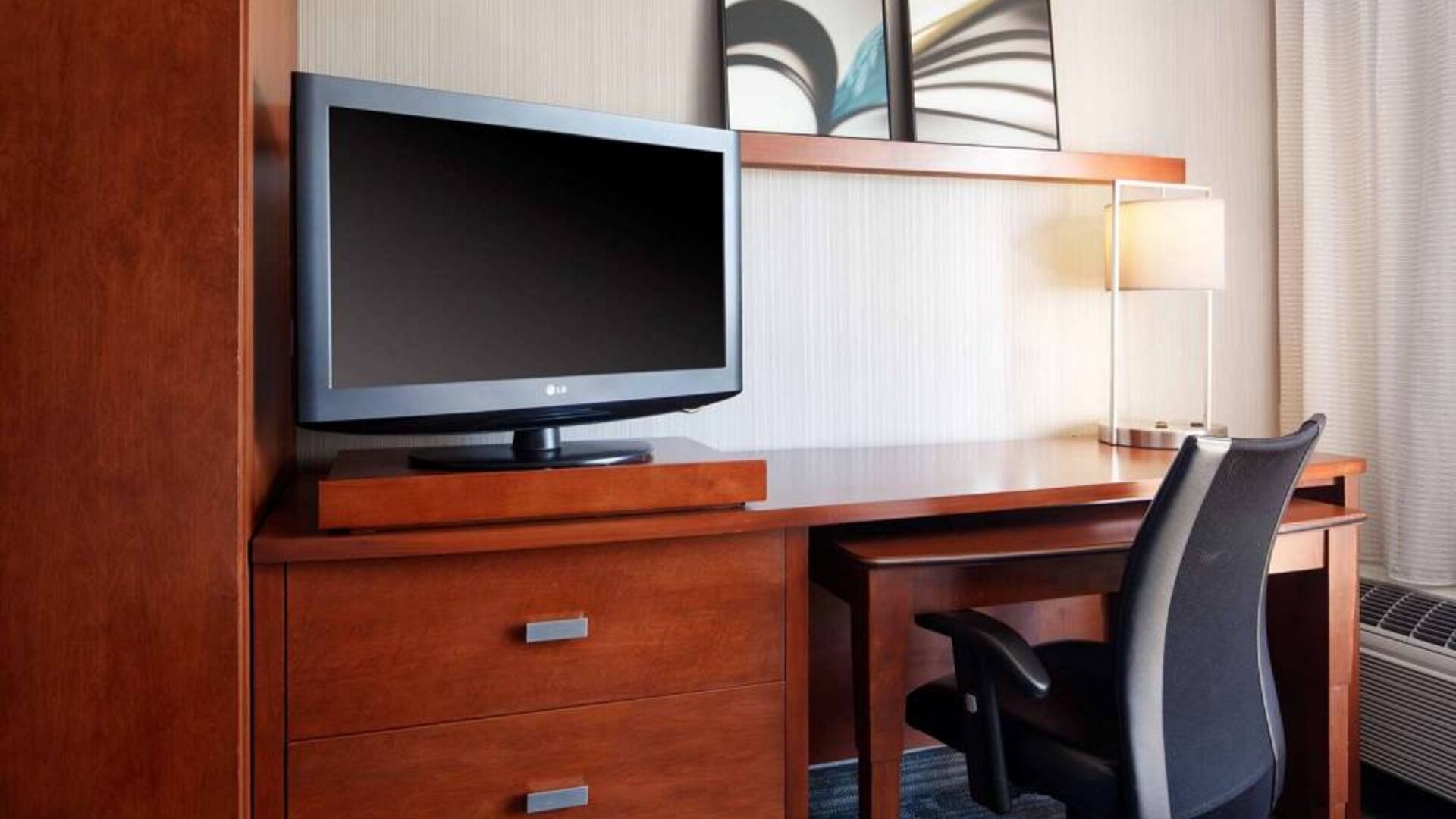 Sonesta Select Boston Milford guest room workspace, with desk, chair, lamp, and TV.