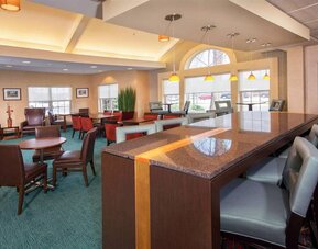 Sonesta ES Suites Charlottesville University’s lobby has extensive seating, including armchairs, table seating, and tall stools, plus a wall-mounted TV.