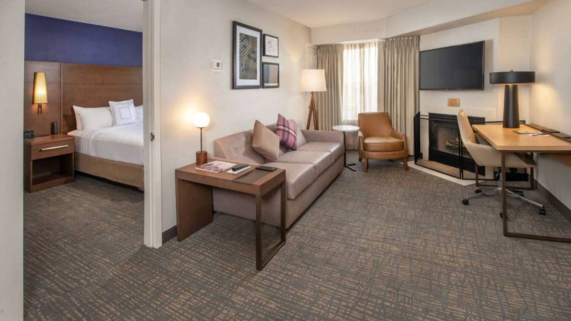 Double bed guest room in Sonesta ES Suites Baltimore BWI Airport, furnished with sofa, chair, fireplace, and television.