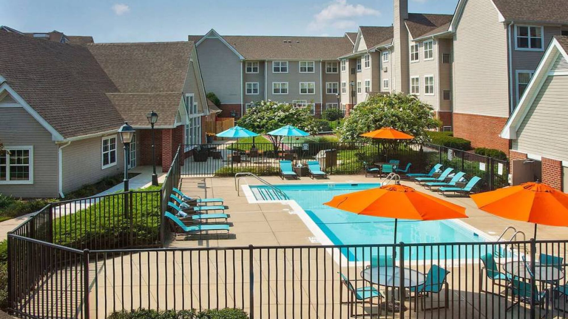 Sonesta ES Suites Baltimore BWI Airport’s outdoor pool is ringed by a fence, within which there are sun loungers, plus shaded tables and chairs.