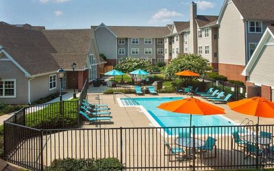 Sonesta ES Suites Baltimore BWI Airport’s outdoor pool is ringed by a fence, within which there are sun loungers, plus shaded tables and chairs.