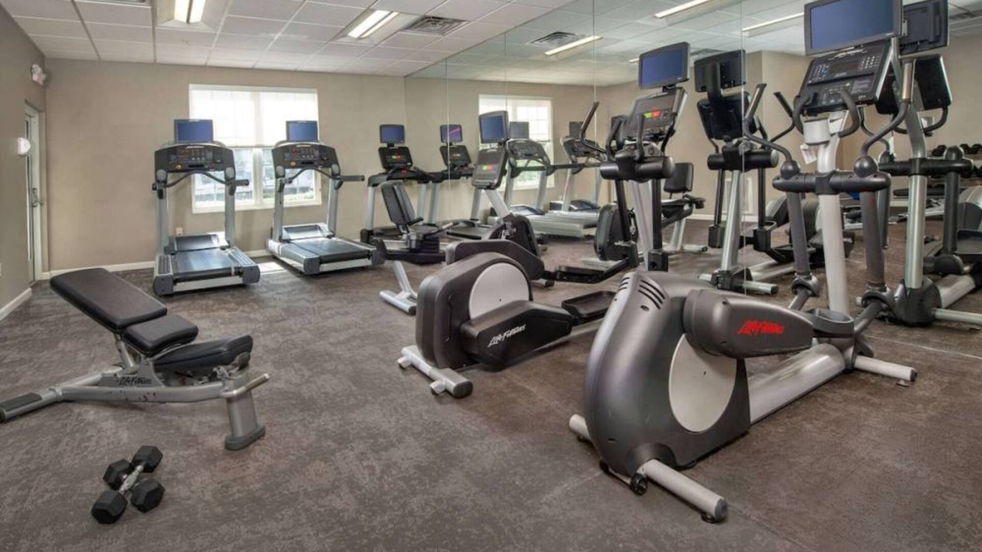 The fitness center in Sonesta ES Suites Baltimore BWI Airport is equipped with free weights and a bench alongside an assortment of exercise machines.