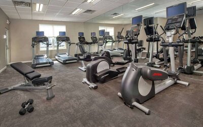 The fitness center in Sonesta ES Suites Baltimore BWI Airport is equipped with free weights and a bench alongside an assortment of exercise machines.