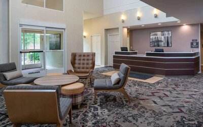 The lounge in Sonesta ES Suites Nashville Brentwood’s lobby features a quartet of comfy chairs, a snazzy carpet, and a coffee table. 