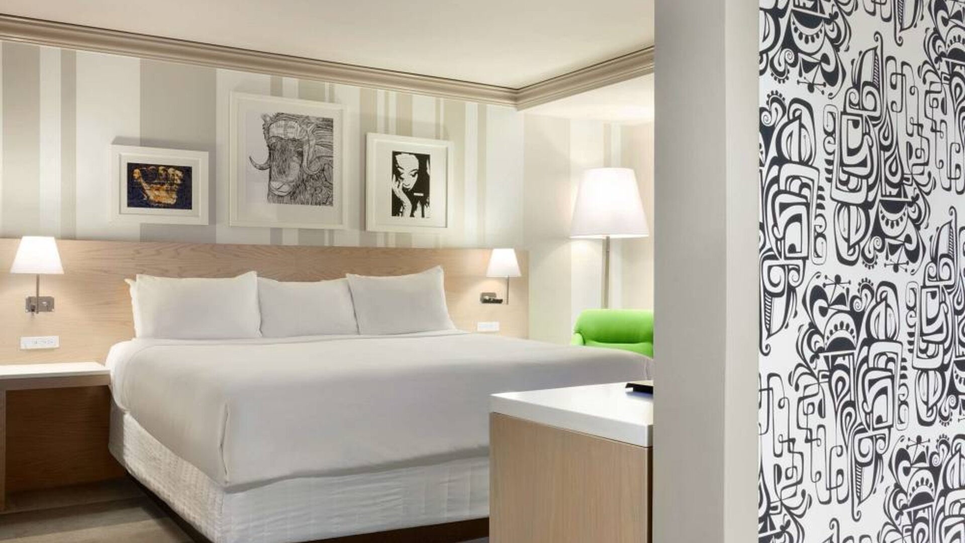 King bed guest room in Royal Sonesta Minneapolis Downtown, featuring art on the wall and a bedside armchair.